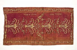 Reader's desk cover (?), faded wine red silk, floral gold embroidery, in secondary use, dedicated in the names of Samuel Shabbetai and Myriam Sh