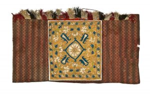 Tik (Torah case) wrapper, cotton in brown shades, with geometric design in vertical stripes, fringe trim at upper border, ochre silk satin centrepiece in secondary use, embroidered with blue, light green and white silk threads, with concentric floral ornament in large scale and bold design, at time of dedication to the Ioannina Congregation.