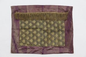 Tik (Torah case) wrapper, silk brocade centrepiece with lattice pattern, in secondary use, decorated with ochre fringe trim, purple silk border.