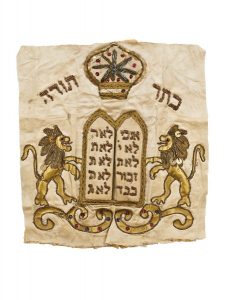 Torah mantle fragment, cream silk with gold embroidery and applique work, depicting Jewish motifs of the Tablets of the Covenant, Crown of the Torah and flanking lions.