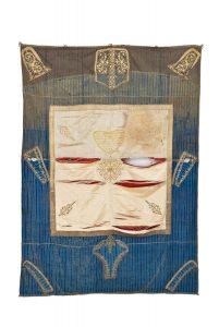 Torah ark curtain, cream silk centrepiece with gold embroidery and dedicatory inscription, made from wrapper, bordered by striped blue cotton trimmed with parts of gold embroidered garment, dedicated by Judah Menahem HaCohen and his wife Esther in memory of their daughter Hannah to the New Congregation, Ioannina.