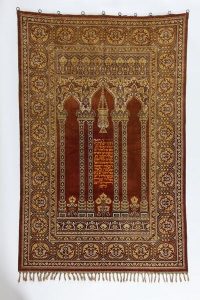 Torah ark curtain, cotton rug in brown shades, made from Muslim prayer rug, orange embroidered inscription, dedicated by Leah, wife of Judah Elijah Jacob, to the Old Congregation, Ioannina.