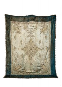 Torah Ark curtain, centrepiece made from a faded blue silk bedspread with laid and couched gold embroidery, dedicated by Meir Pinto and his wife Dodon in memory of their son Alberto.