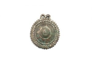 Circular brass pendant with eight-pointed star in circle.