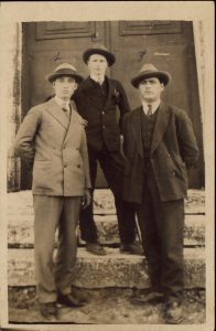 Three men standing on steps of a building.