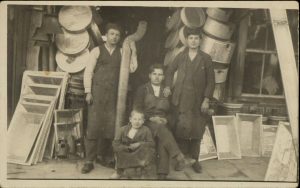 Three men and a boy outside coppersmith's shop.