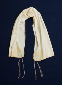 Prayer shawl, handwoven white cotton with light blue square corner reinforcements.