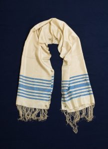 Prayer shawl, white fabric with light blue stripes, embroidered ornament at the neck.