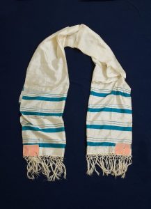 Prayer shawl, white silk with cerulean blue stripes along the edge, salmon square corner reinforcements.
