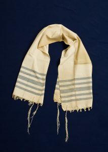 Prayer shawl, white silk with light blue stripes along the edge, white square corner reinforcements.
