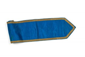 Narrow cornflower blue satin band, trimmed with gold braid, intended for use as sash or Torah binder (?).