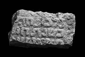 Fragment of a marble stele bearing an inscription in high relief letters.