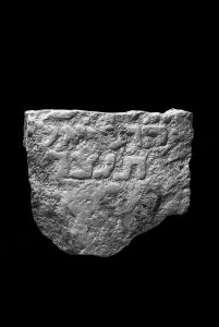 Fragment of a marble stele bearing an inscription in high relief letters.