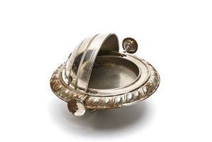 Small metal serving tray with stamped decoration, circular base with revolving, hemispherical lid, used probably as ashtray.