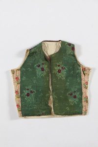 Dark green silk brocade with floral bouquet pattern at the front, rear side made of white cotton with blue and green stripes, probably belonged to a member of the the local Jewish community.