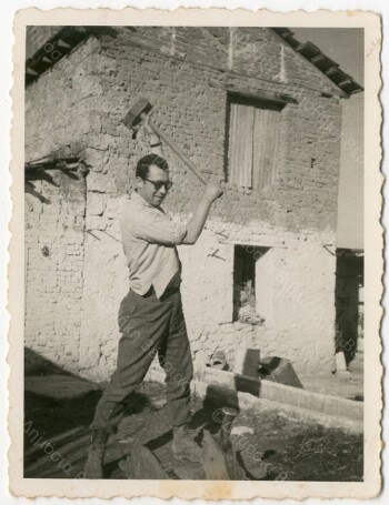 Konstantinos Velliadis cutting wood in front of his house