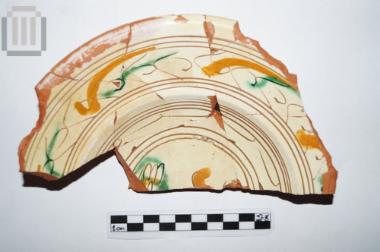 Part of a glazed plate with painted and incised decoration