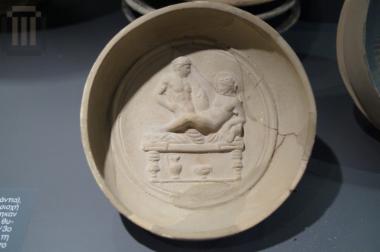 Omphalos phiale decorated with erotic scene in relief