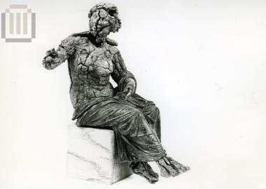 Αγαλμάτιο γυναικείας μορφής, καθισμένης σε βράχο.