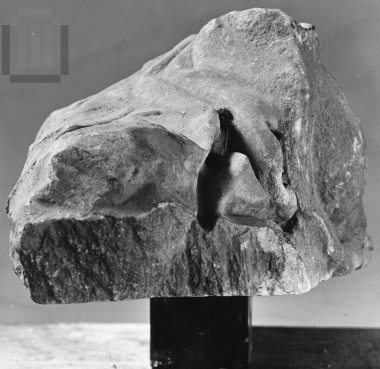 Τμήμα βράχου σκεπασμένο με ιμάτιο και δίπλα το κράνος ενός πολεμιστή