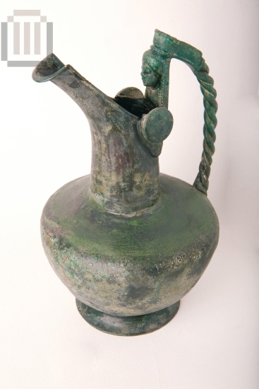 Beaked jug with a female bust at the handle.