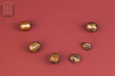 Seven gilded clay beads of a necklace