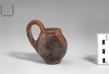 Clay juglet with an almost vertical rim and a raised handle