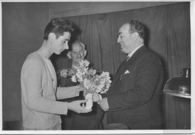 Ο νομάρχης Θεσσαλονίκης κ.Μανουσόπουλος δέχεται λουλούδια από μαθητή της Α.Γ.Σ. υπό το βλέμμα του Θεόδωρου Λίτσα