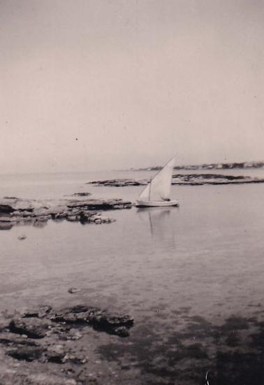 Άποψη της παραλίας στη Γλυφάδα και μικρή βάρκα με πανί.