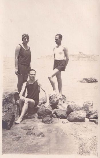 Δύο άνδρες και γυναίκα με μαγιό σε ακτή.