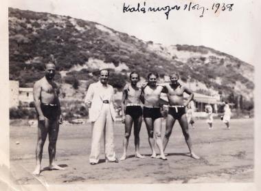 Τέσσερις άνδρες με μαγιό και ένας με κοστούμι στην παραλία του Κατακόλου.