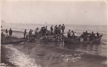 Κάτοικοι των Γανοχώρων ή Γανοχωρίων της Ανατολικής Θράκης (περιοχή Ιερού Όρους στην Προποντίδα), σε ξύλινη εξέδρα, φορτώνουν μπαούλα και βαρέλια σε πλεούμενο στην παραλία, εγκαταλείποντας τον τόπο τους.