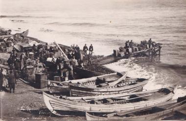 Κάτοικοι των Γανοχώρων ή Γανοχωρίων της Ανατολικής Θράκης (περιοχή Ιερού Όρους στην Προποντίδα) σε ξύλινη εξέδρα γεμάτη μπαούλα και βαρέλια. Άλλοι στην ακτή, όπου έχουν σωρευτεί οι οικοσκευές, καθώς ετοιμάζονται να εγκαταλείψουν τον τόπο τους. Δίπλα τους πλεούμενα.