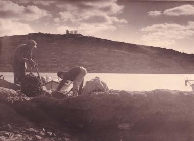 Άποψη από τα βορειοδυτικά του ακρωτηρίου του Σουνίου, με τον ναό του Ποσειδώνα. Σε πρώτο πλάνο, ψαράδες ετοιμάζουν τα δίχτυα τους.