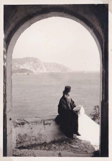 Μοναχός διαβάζει στη μονή του Ποντικονησίου. Στο βάθος η θάλασσα.