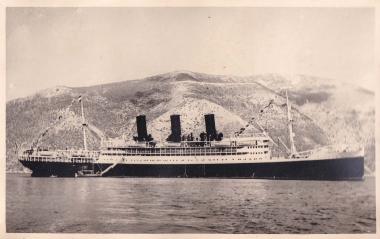 Επιβατηγό πλοίο αγκυροβολημένο αρόδο στην Ιθάκη και δίπλα του λέμβος για τη μεταφορά επιβατών στην ξηρά.