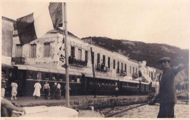 Λέμβος με επιβάτες πλοίου προσεγγίζει την προκυμαία στο Κατάκολο, όπου σταθμεύει συρμός τρένου.