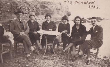 Συντροφιά ανδρών και γυναικών σε τραπέζι παραλιακού κέντρου σε βραχώδη ακτή του Παλαιού Φαλήρου.