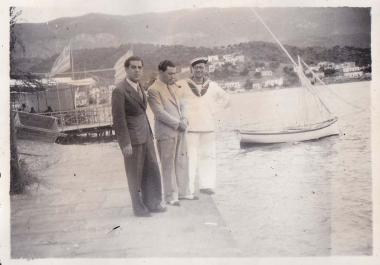 Τρεις άνδρες ( ο ένας με στολή ναύτη) σε παραλία του Πόρου.