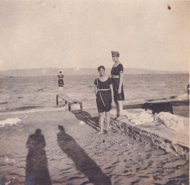 Δύο γυναίκες σε παραλία του Λαυρίου και, στο βάθος, κορίτσι σε μικρή εξέδρα.