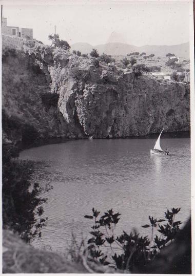 Βάρκα με πανί σε βραχώδη ακτή.