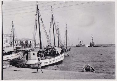 Βάρκες και καΐκια στο ενετικό λιμάνι των Χανίων και στο βάθος πλοίο που αναχωρεί.