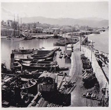 Το λιμάνι και μέρος της πόλης του Ηρακλείου από τον Κούλε. Η σιδηροδρομική γραμμή που διακρίνεται συνέδεε το λιμάνι με το λατομείο του Εσταυρωμένου στον Ξηροπόταμο και λειτούργησε κατά την περίοδο 1922-1937 για να διευκολύνει την κατασκευή του νέου λιμανιού στο Ηράκλειο.