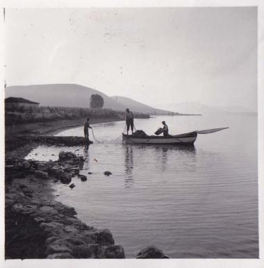 Ψαράδες σε βάρκα απλώνουν δίχτυα σε ακτή.