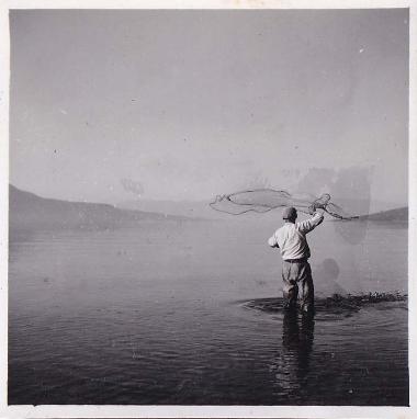 Ψαράς πετάει το δίχτυ του στο νερό.