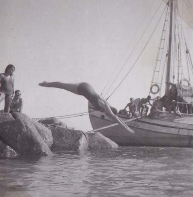 Γυναίκα βουτά στη θάλασσα δίπλα σε καΐκι, δεμένο σε παραλία της Δήλου.