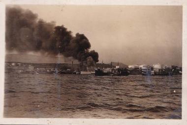 Φωτιά σε πετρελαιφόρο πλοίο, ελλιμενισμένο μαζί με άλλα στην Δραπετσώνα∙ εγκαταστάσεις αποθήκευσης καυσίμων διακρίνονται στα δεξιά.