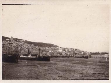 Η Άνω Σύρος, η Ερμούπολη και το λιμάνι της από τη θάλασσα. Περίπου στο κέντρο της εικόνας, διακρίνεται ο ναός του Αγίου Νικολάου στα Βαπόρια.